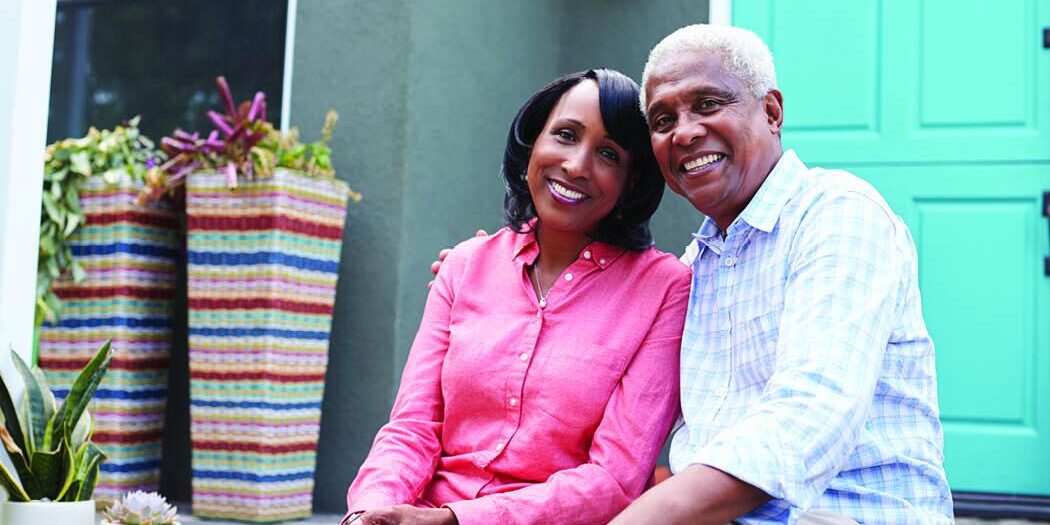 mature couple sitting on steps in front of home