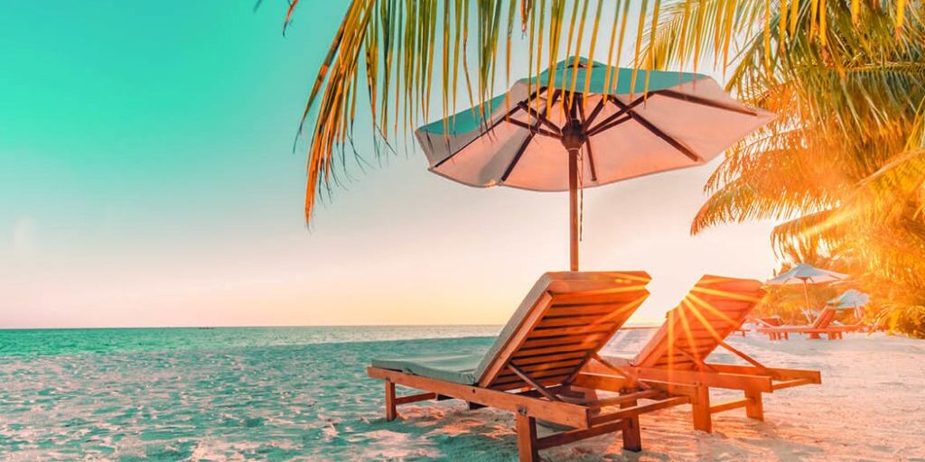sun rising on beach with two empty beach lounge chairs